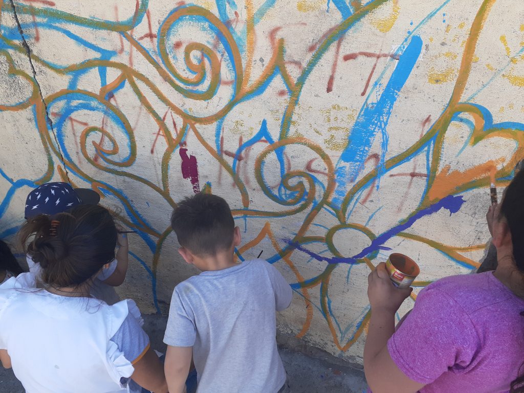 Niños y adultos del Núcleo Barrial de Costa Esperanza pintan un mural en su barrio,